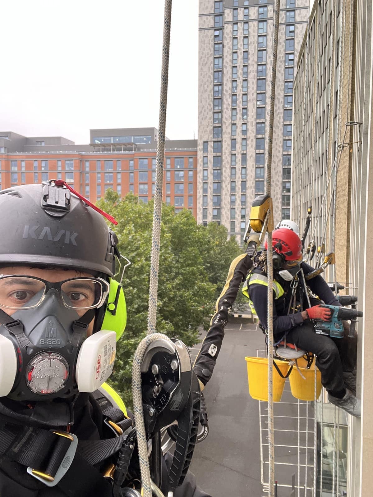 A BOVI Access technician in a helmet, harness and respirator at height